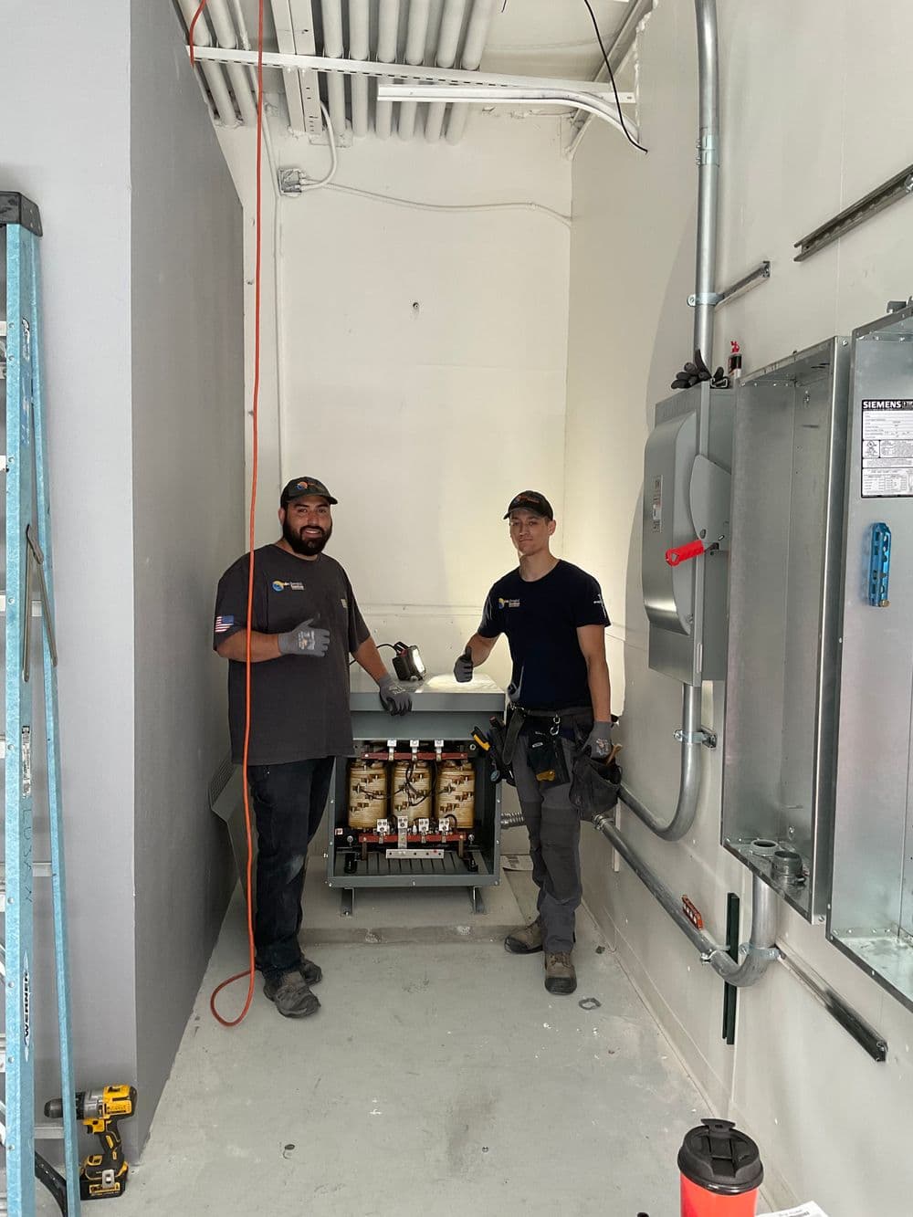 Two technicians working together in a well-lit utility room, with tools and equipment visible.