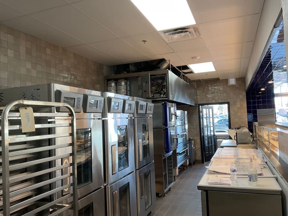 Modern commercial kitchen featuring stainless steel appliances and organized workstations.