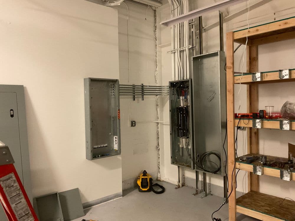 Electrical panel installation in a commercial storage room with tools and equipment.